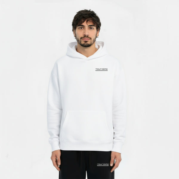 Homme portant un hoodie blanc avec le logo "TOURISMO" à gauche de la poitrine et pantalon noir assorti