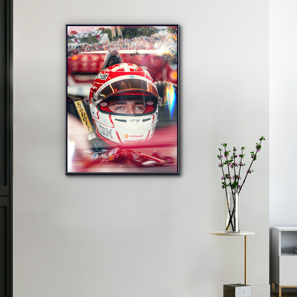 Toile F1 Charles Leclerc accrochée au mur avec cadre noir, regard intense à travers le casque rouge Ferrari