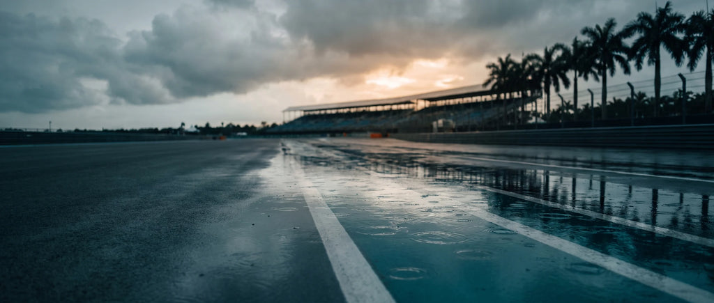 Pit lane inondée d'un circuit tropical sous la pluie, tribune vide au fond