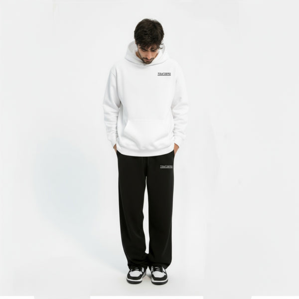 Homme regardant vers le sol portant un hoodie blanc et pantalon noir assorti avec logo “TOURISMO”